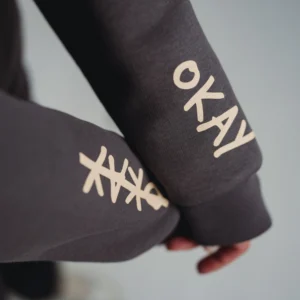 Nahaufnahme der bedruckten Ärmel auf dem grauen Mo-Torres Zipper Hoodie mit OKAY Schriftzug