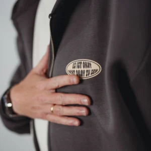 Detailansicht des ovalen Brust-Logos auf dem grauen Mo-Torres Oversized Zipper Hoodie